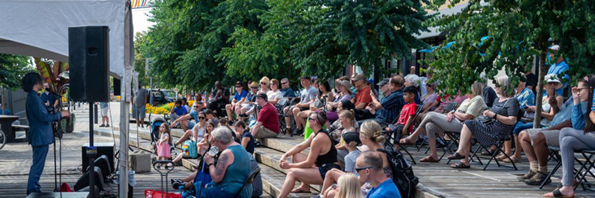 Crowd gathered at outdoor plaza watching a single musician perform.
