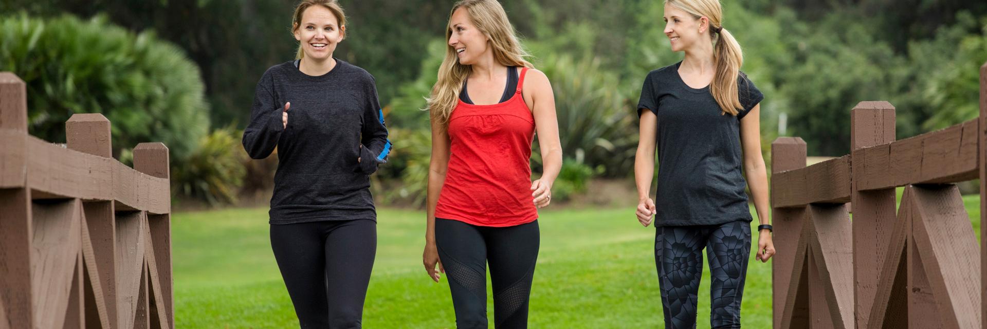 three ladies walking over a bridge