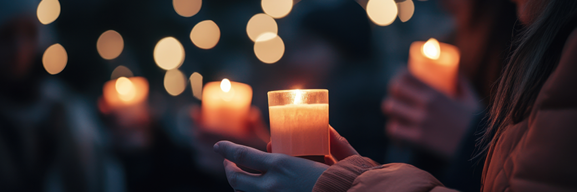 People holding candles in remembrance at a ceremony.