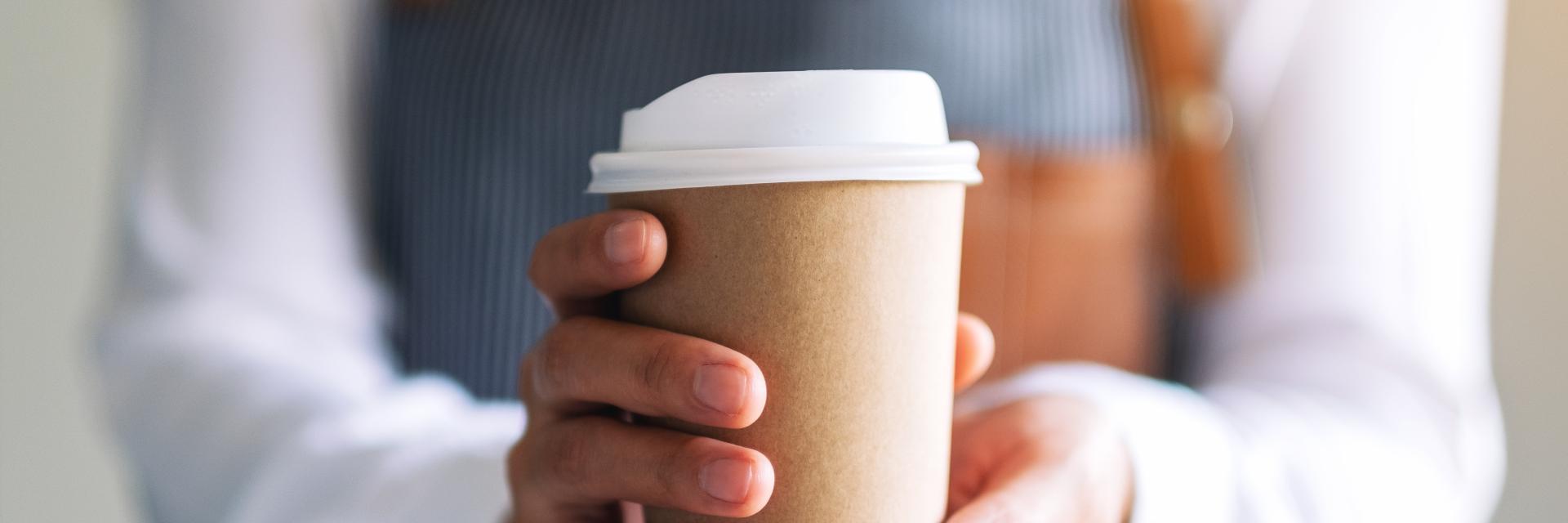 person holding a coffee cup to give away