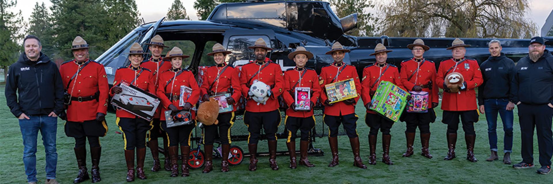 RCMP standing with Sky Helicopter holding presents