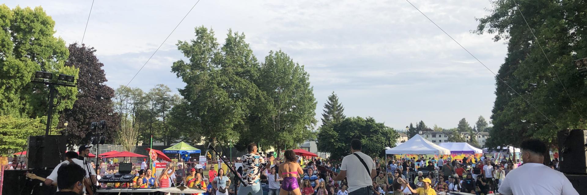 Band playing in front of crowd on outdoor stage.