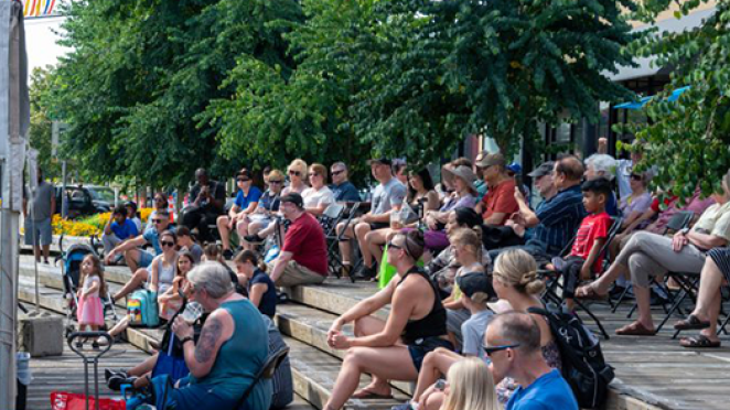 Crowd gathered at outdoor plaza watching a single musician perform.