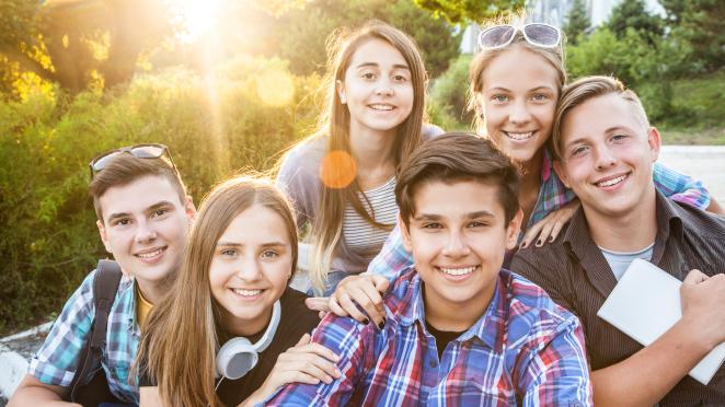 Group of six teenagers hanging outside in a park.