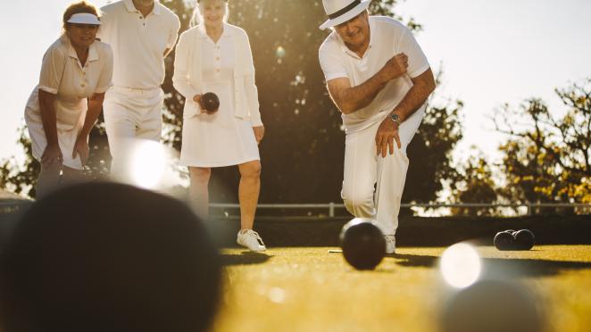 Group of seniors lawn bowling outdoors.