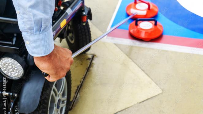 Individual in a wheelchair participating in floor curling.
