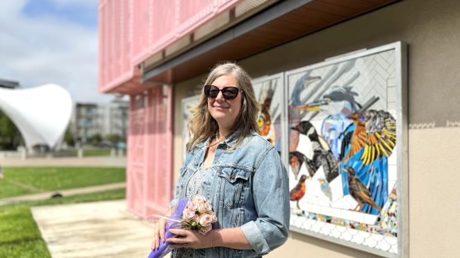 Artist stands with her mosaic mural