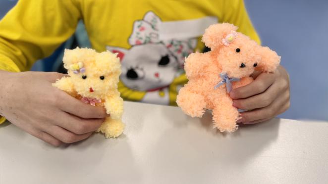 Child holding two homemade stuffed animals they created.