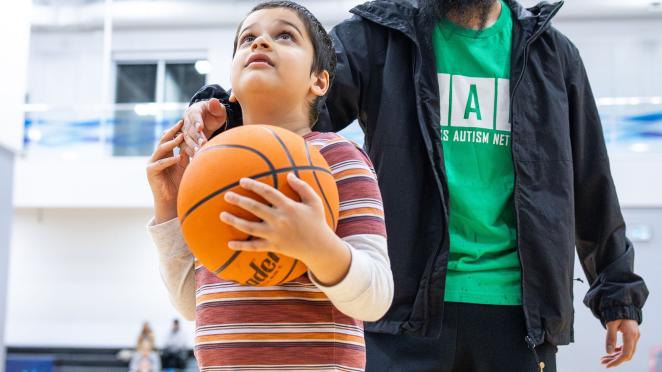 child playing basketball with support