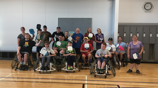 group of people playing wheelchair pickleball