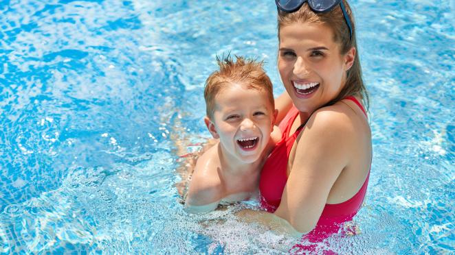 Mom in red bathing suit swimming with son