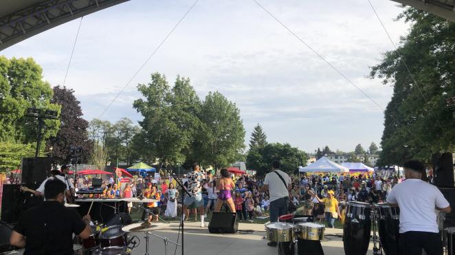 Band playing in front of crowd on outdoor stage.